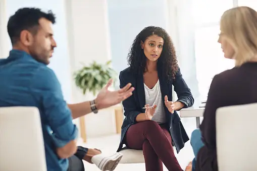 A group of people sitting around talking to each other.